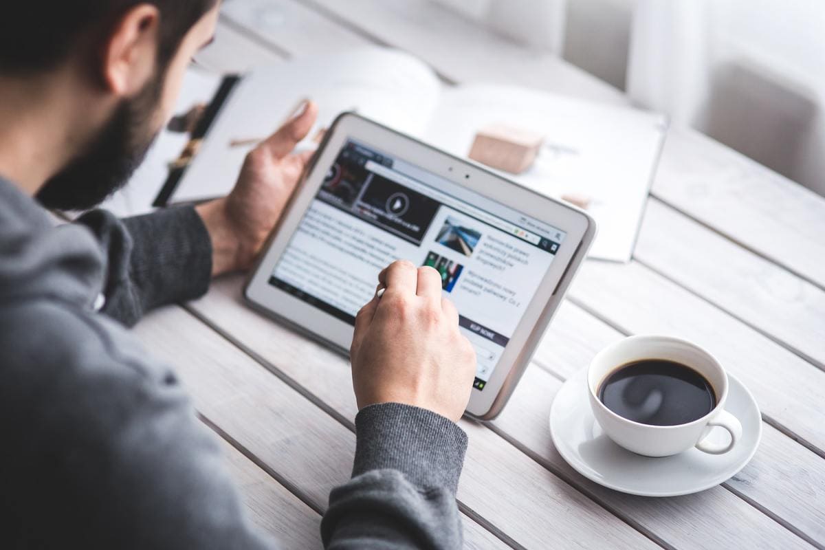 Man drinking coffee and looking at tablet