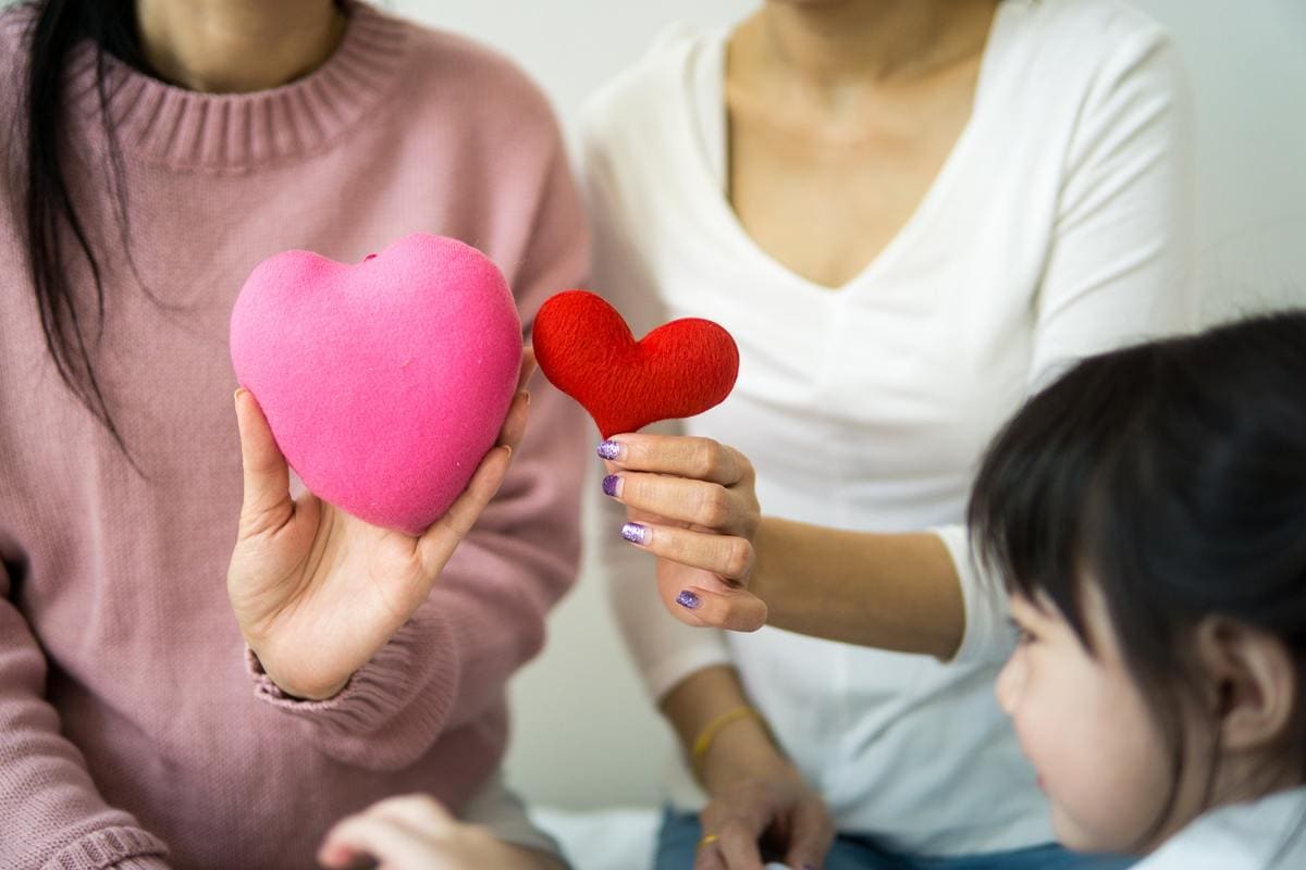 Two women holding toy hearts