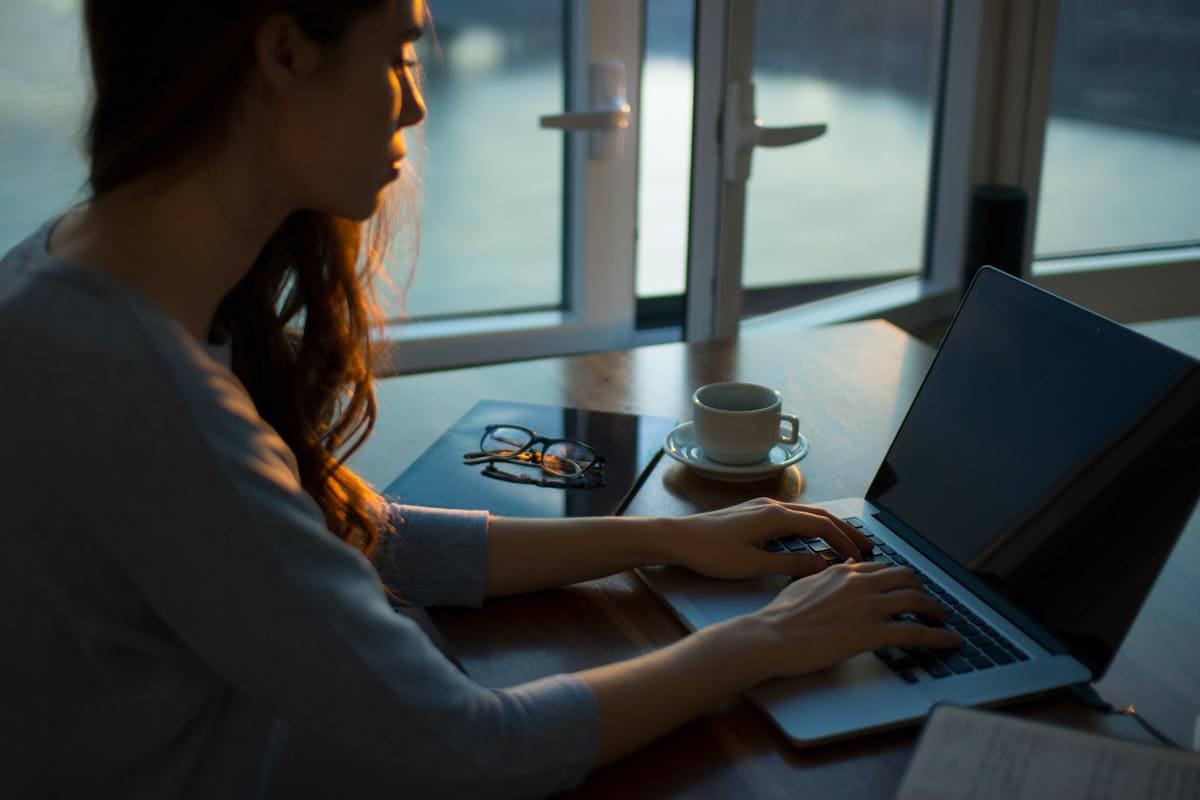 Women sitting beside table and using laptop